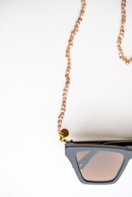 Load image into Gallery viewer, Close up shot of the freshwater pearl chain from BRAND. The Label in pink champagne colour. Attached to stylish sunglasses to keep your eyewear safe.  
