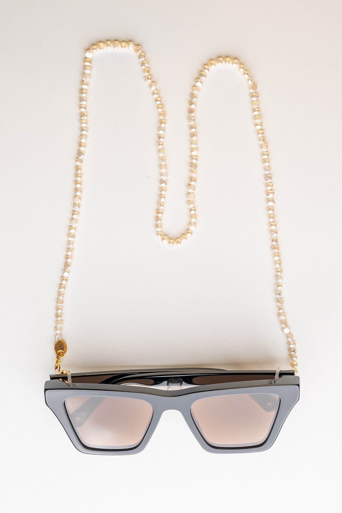 BRAND. The Label Frame chain in natural freshwater pearl. Pictures in the Ivory colour with gold hardware. Can be used as a frame chain or sunglass chain to protect your eyewear. A unique piece from BRAND. The Label resort wear collection. 